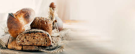 Assorted bread products on a wooden table. variety of wheat and rye bread are presented on a wooden relief background. Copy spaceの写真素材