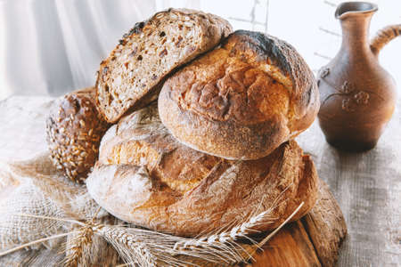 Assorted bread products on a wooden table. variety of wheat and rye bread are presented on a wooden relief backgroundの写真素材