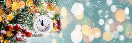 white alarm clock on the background of a bright Christmas tree with a garland and a bokeh. Christmas...