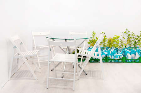 White garden furniture with an installation of green plants. A symbol of outdoor recreation and in...