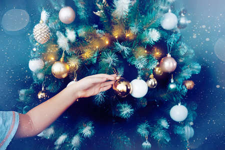 childs hands decorate the Christmas tree. Colorful toys on the Christmas tree