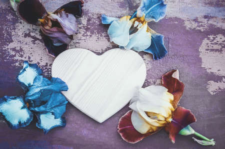 place for a heart-shaped text on a wooden background with multi-colored iris flowers of different...