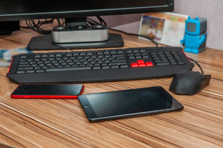 old red tablet with a crack on the screen is lying on a wooden table. The workplace of a student or...