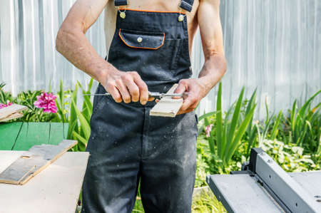 turner measures the board with a tool. saw table. An experienced carpenter is ready to cut a wooden...