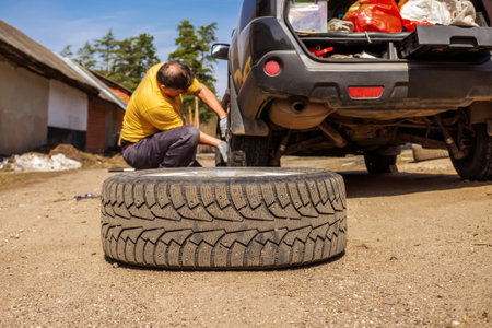 Replacing a spare wheel on the road with your own hands. The driver changes the wheel without the help of an auto repair shop. real life.の写真素材