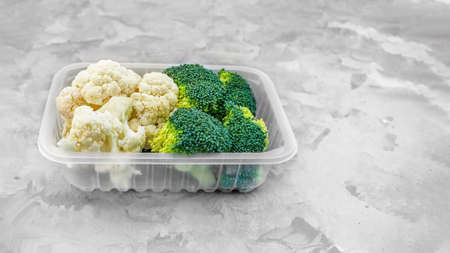 lot of broccoli and cauliflower on the table in a plastic box on a gray background. copyspace.