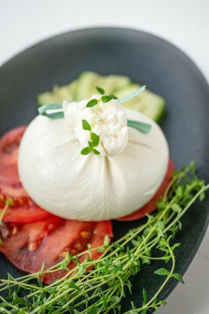 Italian cheese burrata, tomatoes and vegetables close-up. A layer of mozzarella with creamy straticella inside.の写真素材