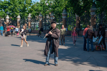 June 7, 2015 St. Petersburg, Russia : An elderly man plays a flute for tourists at the fence of the...