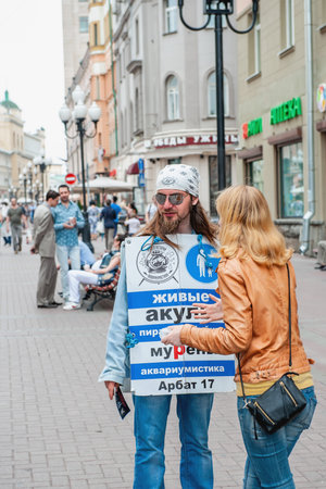 Moscow, Russia, 2015.07.09 A street advertiser is talking to a woman. Advertisement for the Aquarium History Museum on a city streetのeditorial素材
