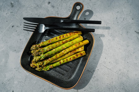 Fresh green asparagus. Cooking healthy food on a beautiful plate that resembles a grill pan. Bunches of green asparagus, top view. Copy space.の写真素材