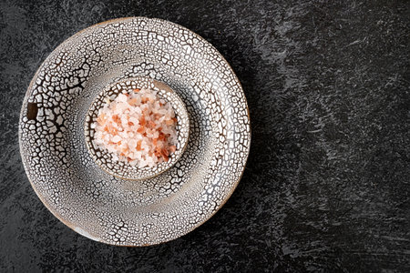 Himalayan pink salt in crystals on an elegant handmade plate. Himalayan pink salt for eating and bathing. Top view, flat lay. Copy spaceの写真素材