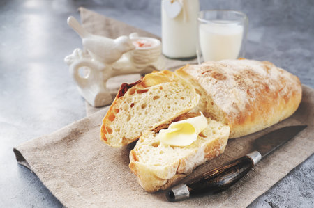 Craftsman sliced toast bread with butter on a wooden cutting board and milk. Simple breakfast on a gray concrete background. Close-up view.の写真素材