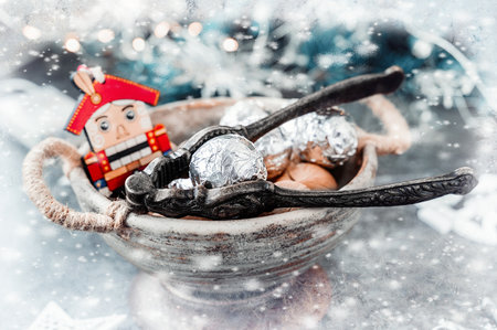 Decorated nuts and nutcracker. Wooden Nutcracker. Wooden Christmas toy with nuts in shell and silver paper on a Christmas background.の写真素材