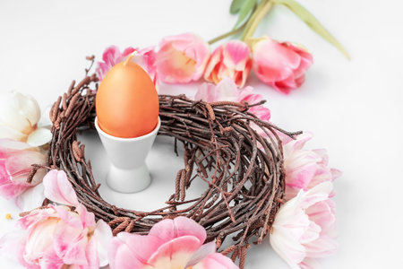 Candle in the form of an Easter egg in a nest. Easter decoration on a wooden table.