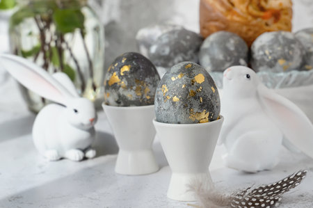 Easter eggs with gold pattern. A plate with Easter eggs and bunny figures. The concept of home...