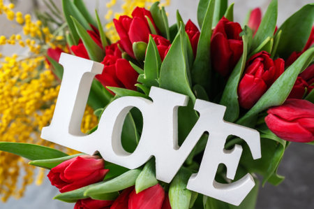 tulips with mimosa and the inscription love. Spring bouquet with mimosa flowers and red tulips - spring concept, spring natural background. Close-upの写真素材