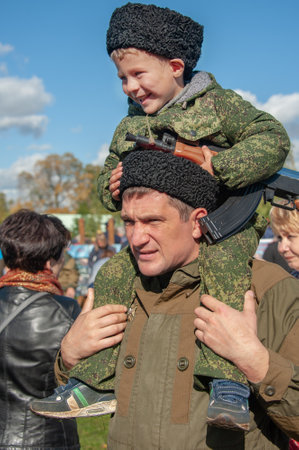 Moscow, Russia - October 1, 2016: little Cossack boy wearing a papakha sits on his fathers shoulders. The boy is upset about somethingのeditorial素材
