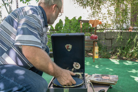 man starts a gramophone. Black gramophone with phonograph record . Hands twist the handle to startのeditorial素材