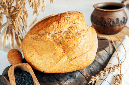 Round white bread. Close-up of white bread with homemade black salt in a wooden scoop on a light...