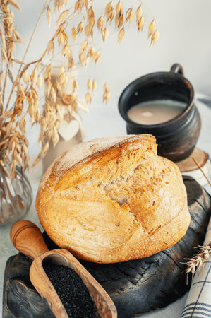 Round white bread. Close-up of homemade white bread with black salt in wooden scoop and milk on light marble background.の写真素材