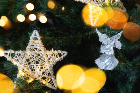 glass angel decorates the Christmas tree. Delicate Angel Ornament on Christmas Tree with Twinkling Lights and Sparkling Tinsel.の写真素材