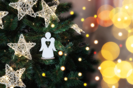 glass angel decorates the Christmas tree. Delicate Angel Ornament on Christmas Tree with Twinkling Lights and Sparkling Tinselの写真素材