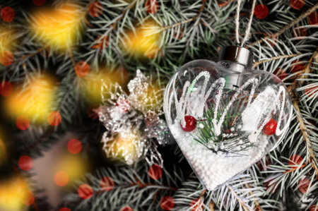 Glass retro Christmas tree toy decorating Christmas tree. Delicate decoration in the form of a transparent glass heart on the Christmas tree with twinkling lightsの写真素材