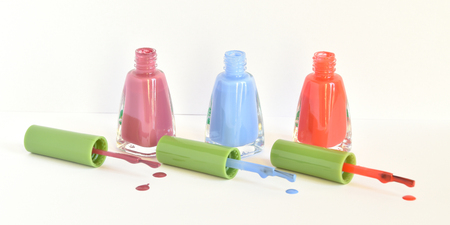 Three similar bottles of different nail polish on white background.の写真素材