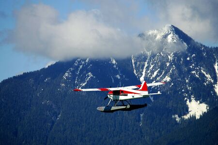 Seaplane fying over mountain, Vancouver, Canadaの写真素材