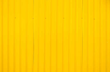 Yellow metal tile fence background. Fence from corrugated board. Yellow slate background. Yellow...