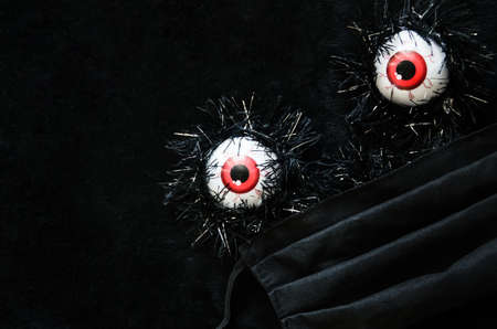 Halloween covid-19 concept. Halloween decor eyeballs in medical protective mask with copy space. Halloween 2020 during the coronavirus pandemic.の写真素材