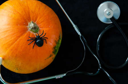 Halloween decor pumpkin with spider and stethoscope with copy space. Medical Halloween in the hospital. Trick or treat festival concept. Doctor pumpkin Halloween card.の写真素材