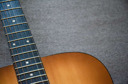 Close-up guitar fretboard with strings isolated on a blurred gray background with copy space. Music...