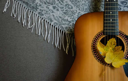 Soft focus on yellow maple leaves and guitar isolated on a blurred gray background with copy space....