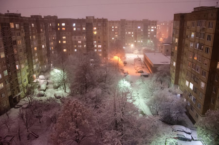 Snowfall in the night city. Blizzard covered houses and streets with snow. Bad weather conditions. Beautiful snowy winter in residential area of Ukraine.の写真素材