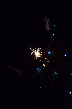 Christmas banner with copy space. Burning sparkler with bokeh light background. Sparks of sparkler on background of New Year's lights. Christmas eve.の写真素材