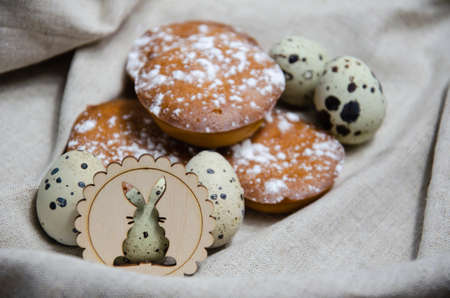 Happy Easter concept. Selective focus muffins, quail eggs and Easter wooden decorative bunny against the background of linen craft fabric. Preparation for the holiday.の写真素材