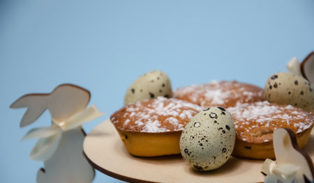Happy Easter decoration: Selective focus muffins and quail eggs on wooden stand with Easter bunnies on blue background with copy space. Preparation for the holiday. Easter holiday banner.の写真素材
