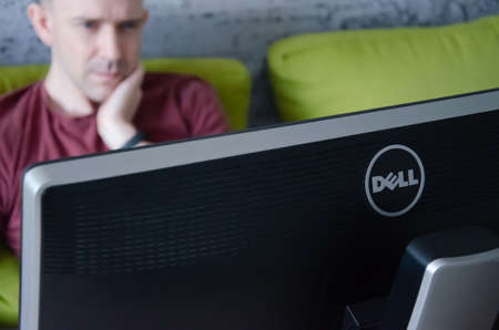 Kiev, Ukraine - March 22, 2021. Dell monitor in front of working caucasian man. Online work at home concept.のeditorial素材