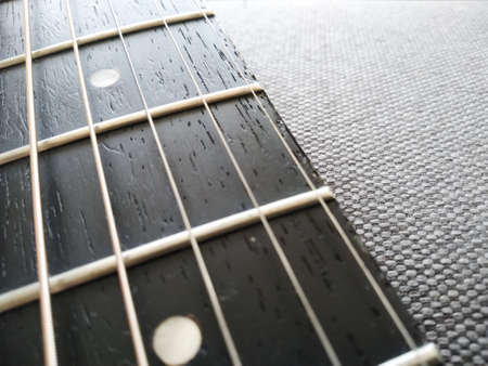 Selective focus guitar fretboard with strings on blurred gray background with copy space. Music...
