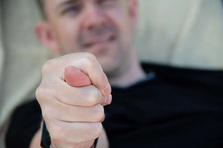 Close-up hand showing fig sign against the background of rude male face. Caucasian man shows fist...