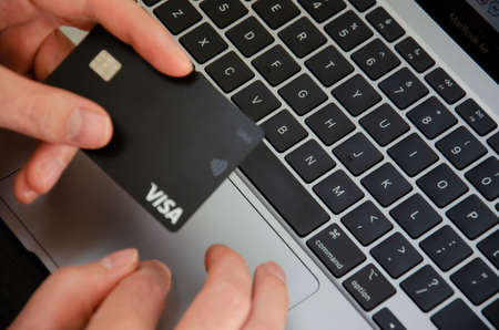 Kiev, Ukraine - September 5 2021. Caucasian man uses MacBook Air M1. Person is shopping with Visa...
