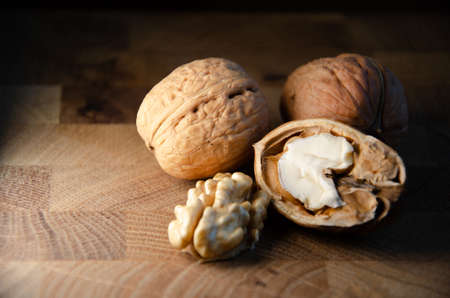 Kernel of young walnut lies next to nuts in shell on brown wooden background with copy space....