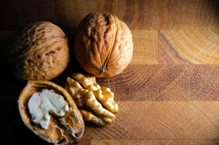 Kernel of young walnut lies next to nuts in shell on brown wooden background with copy space. Harvest of young nuts in autumn. Texture of Walnut.の写真素材