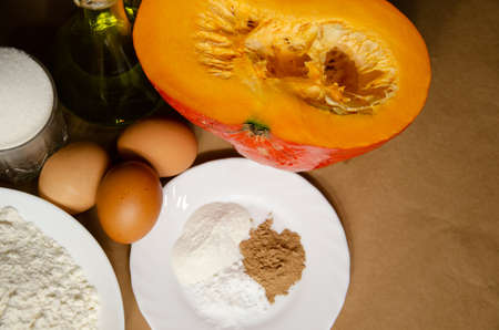 Concept homemade fall baking with pumpkin and food ingredients. Cooking pumpkin pie. Ripe pumpkin, flour, eggs, spices, baking powder, sugar, oil. Step by step instructions. Step 2.の写真素材