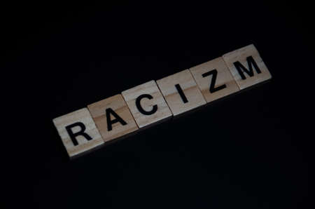 Inscription Racism outlined on dark background with copy space. Selective focus on Lettering Racism....