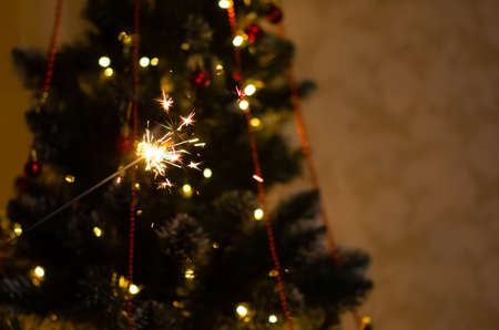 Christmas banner with copy space. Burning sparkler with bokeh light background. Sparks of sparkler on background of New Year's lights. Christmas eve.の写真素材