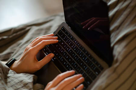 Caucasian man uses laptop. Person works, gets an education, does shopping online on personal computer. Freelance and mobility concept.のeditorial素材