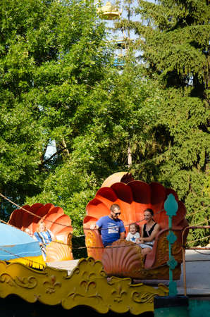Lutsk, Ukraine - August 18, 2021. Old amusement park for children and adults. People have fun on old metal rides. Family vacation in the city. fun concept.のeditorial素材