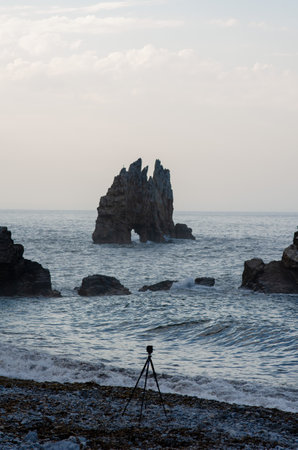 Dramatic coastal landscape featuring a unique rock formation in the sea, captured in soft evening light. Ideal for travel, nature, and outdoor photography projects.の写真素材